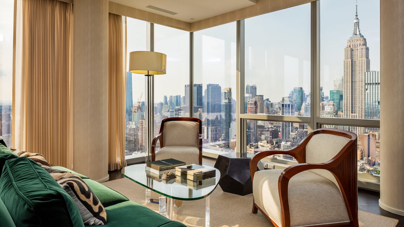 A corner living room with floor-to-ceiling glass facing the Manhattan skyline and the Empire State Building